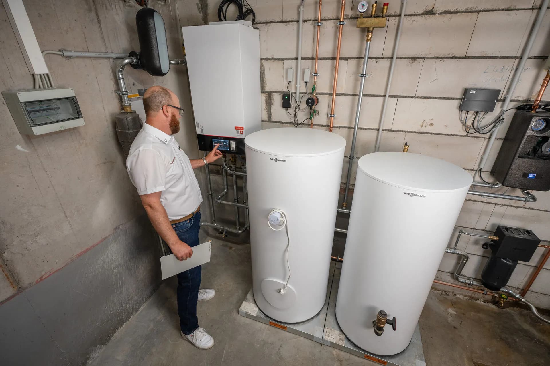 Techniker mit Wärmepumpensystem und Warmwasserspeicher