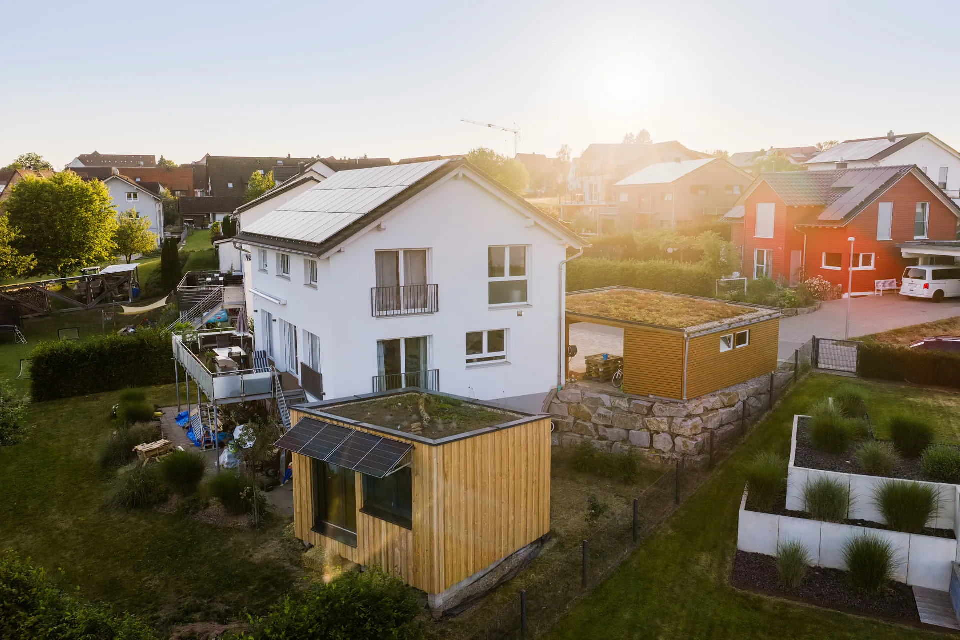 Luftaufnahme einer modernen, energieeffizienten sanierten Wohnsiedlung mit erneuerbaren Energien bei Sonnenuntergang