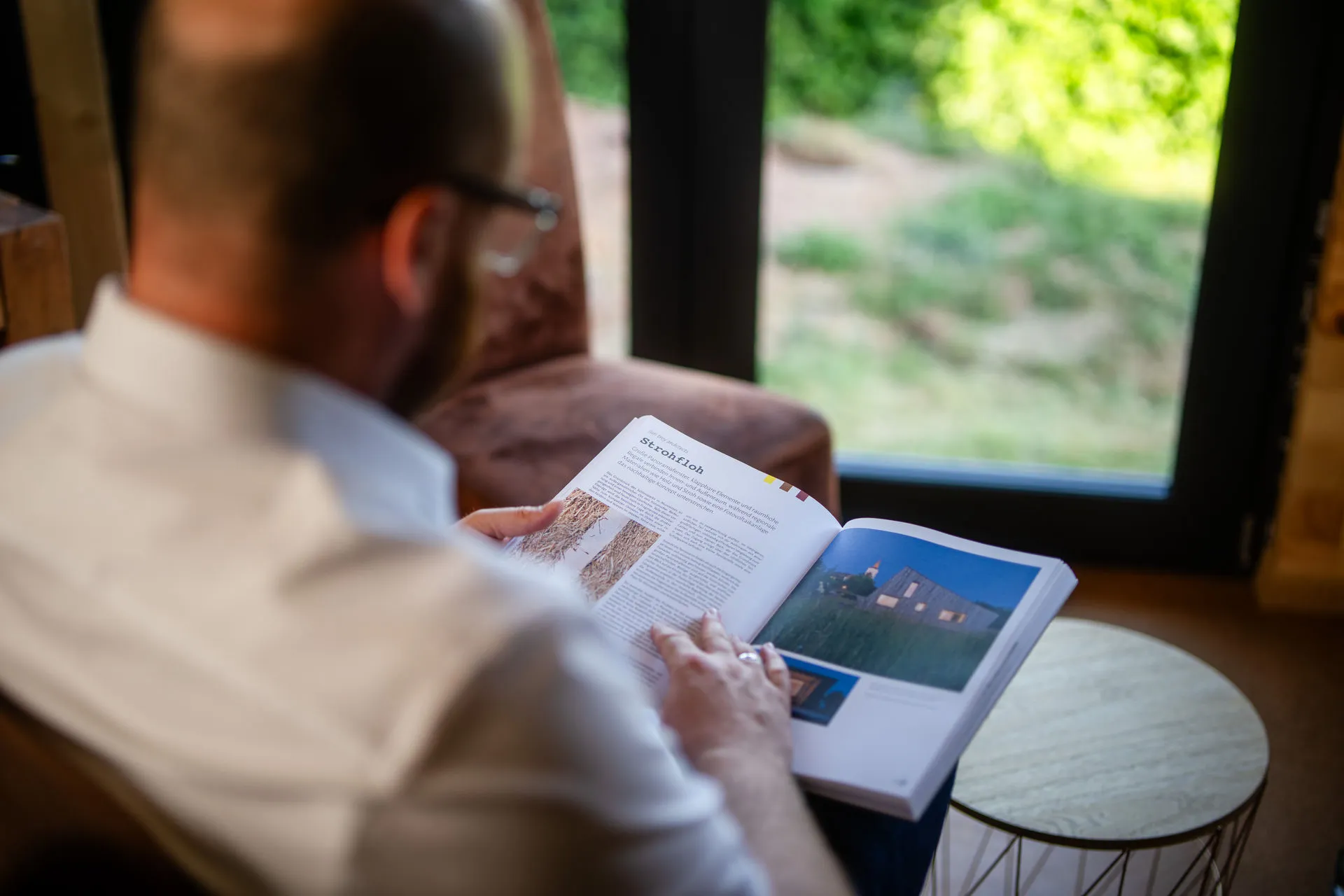 Sebastian Bühler studiert Nachhaltigkeitsdokumente und Zertifizierungsberichte mit grüner Landschaft im Hintergrund